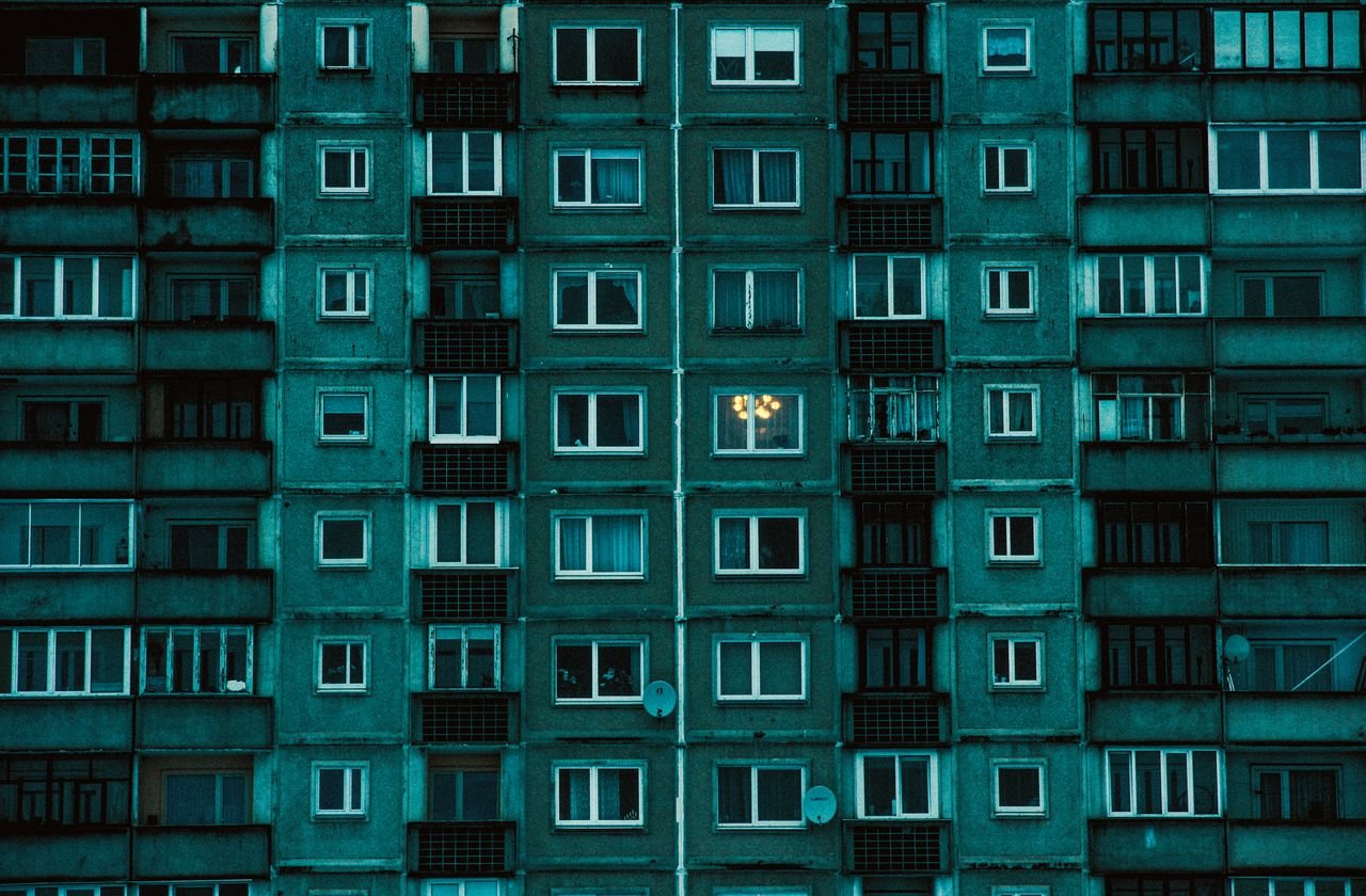 Detailed view of a symmetrical urban apartment building facade with a cold color palette.