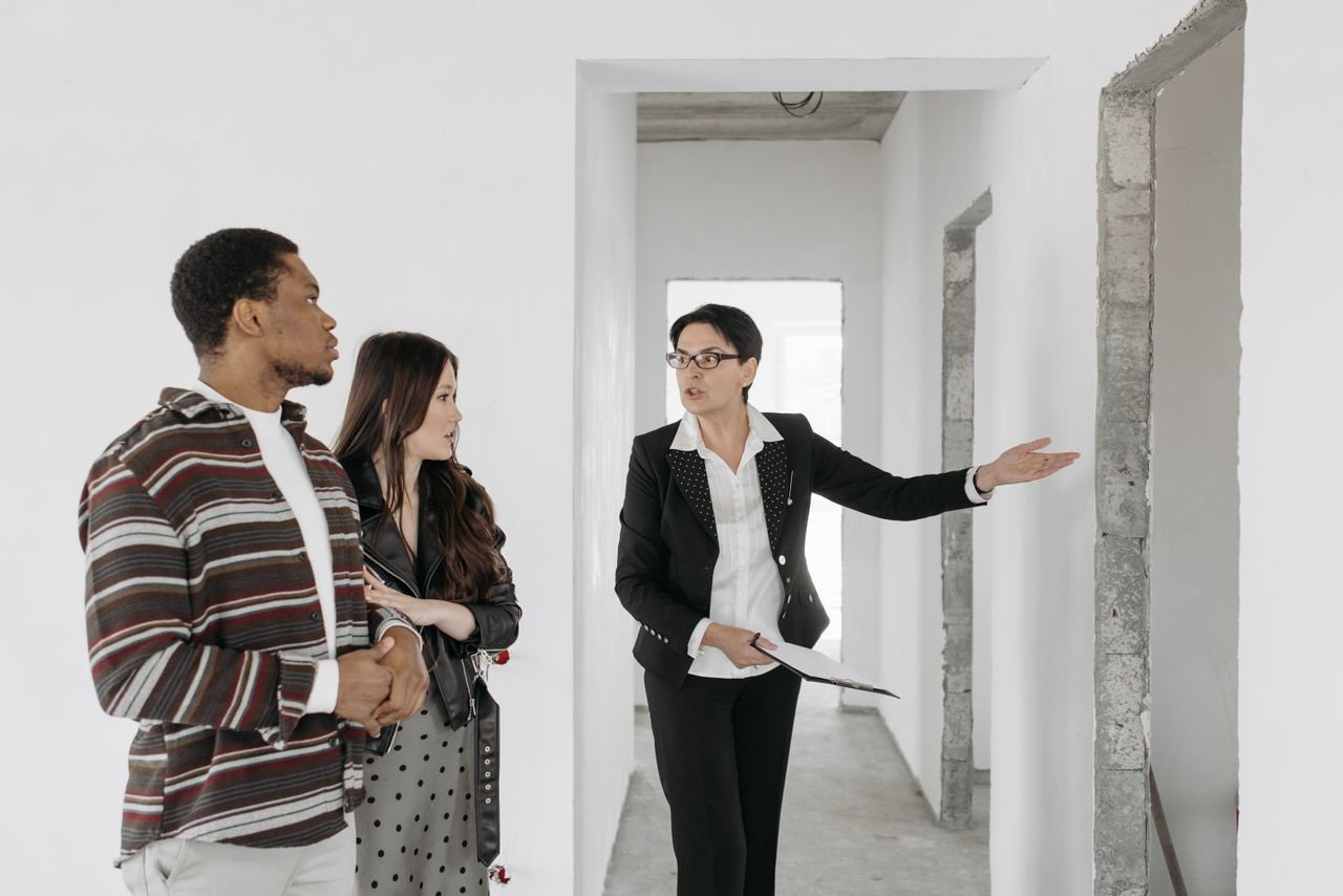 Real estate agent shows a house to a couple, discussing features.